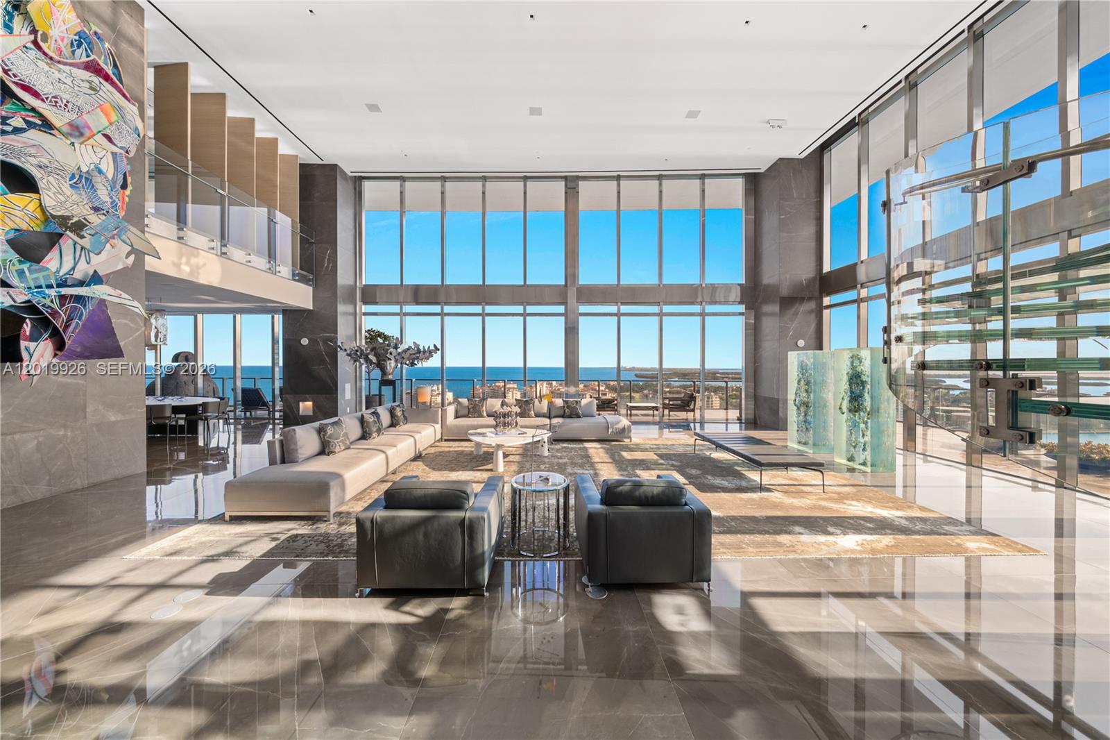 A spacious, double-height living room features floor-to-ceiling windows, marble flooring, and modern furniture — 800 S Pointe Dr # 2204, Miami Beach FL 33139, MIAMI BEACH, FL