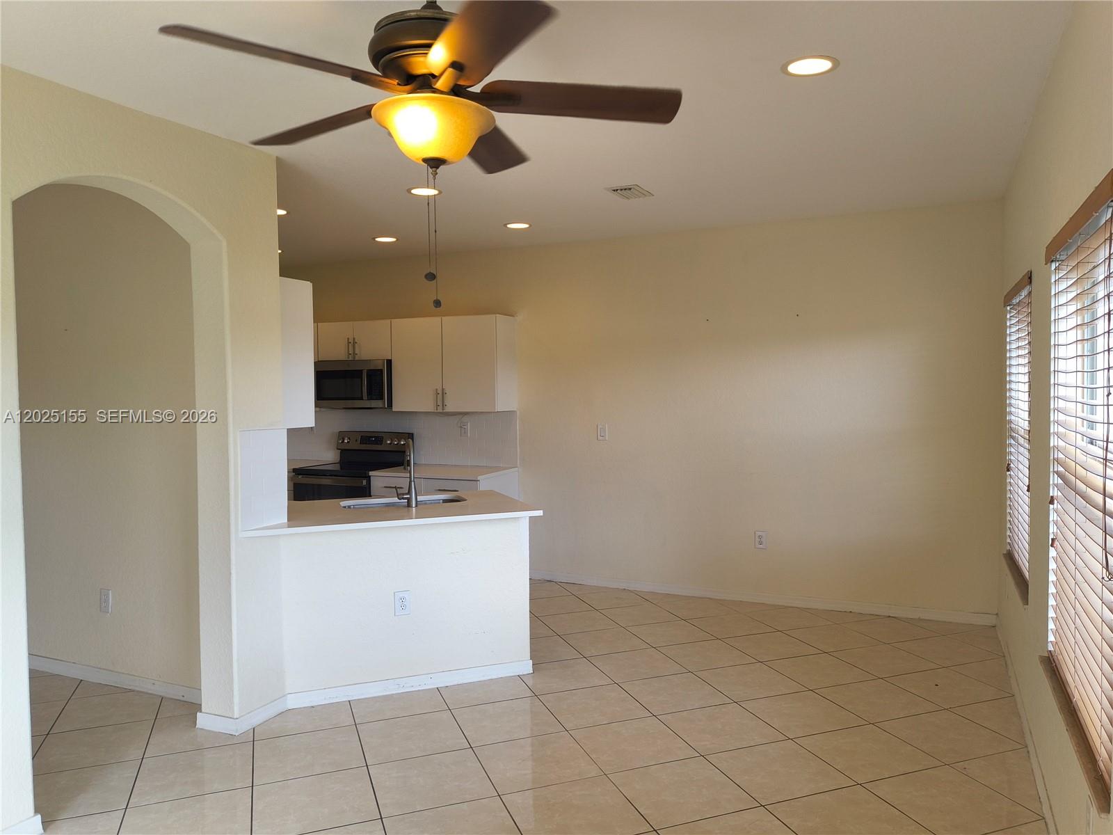 An open-concept kitchen and dining area features tile flooring, white cabinets, and a ceiling fan — 1645 SE 20th Rd # 1645, Homestead FL 33035, HOMESTEAD, FL