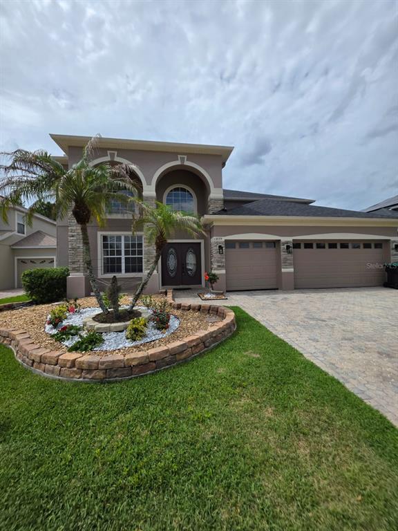 A two-story house with a stone-accented facade, arched entryways, and a paved driveway — 12039 BLAIREMONT WAY, ORLANDO, FL