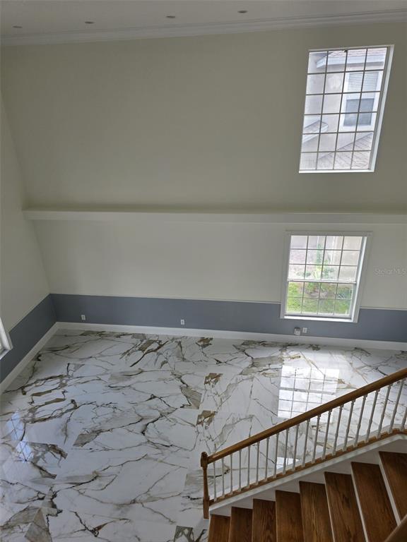 A high-angle view of a room with marble floors, two-toned walls, and a wooden staircase — 12039 BLAIREMONT WAY, ORLANDO, FL