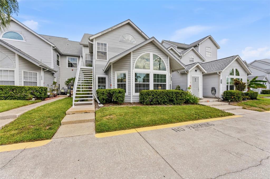 A multi-story residential building with light gray siding, white trim, and an exterior staircase — 12237 ARMENIA GABLES CIR, TAMPA, FL