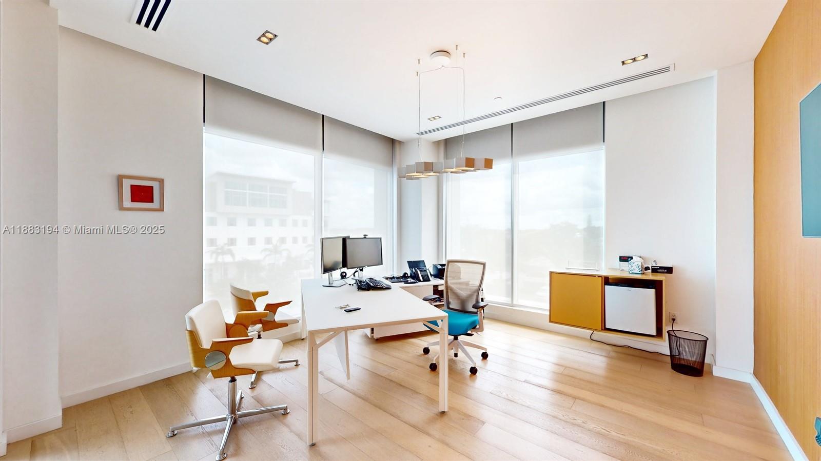 A bright office features a white desk, two chairs, large windows, and light wood flooring — 7950 NW 53rd St # 300A, Doral FL 33166, DORAL, FL