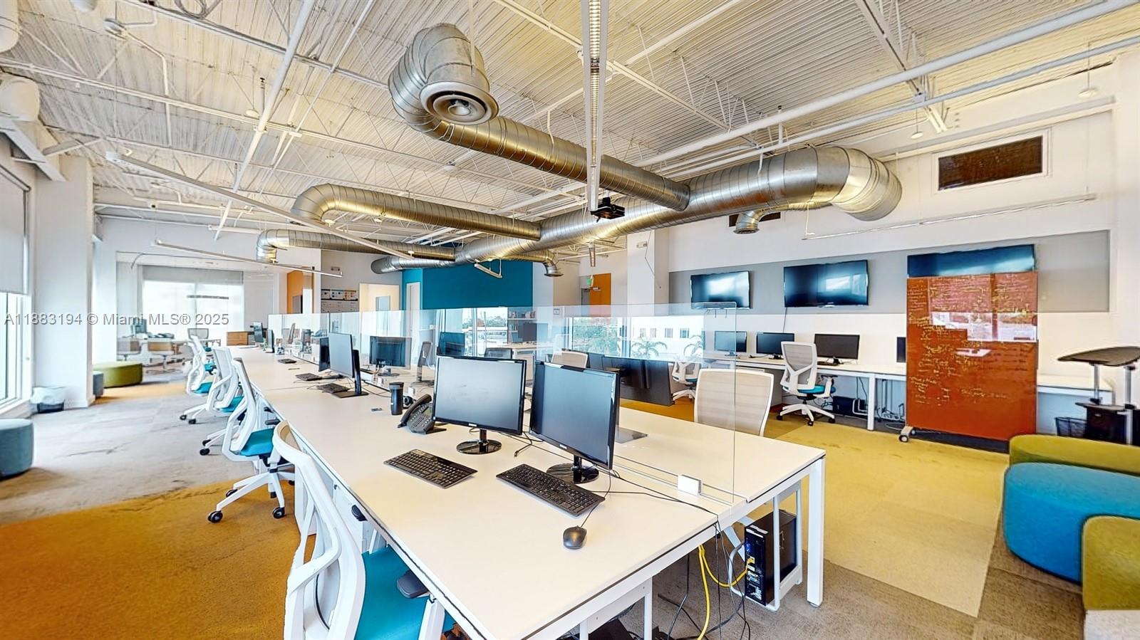 An open-plan office features rows of desks, computer monitors, and exposed industrial ceiling ductwork — 7950 NW 53rd St # 300A, Doral FL 33166, DORAL, FL