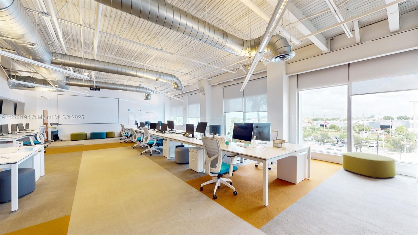 An open-plan office features rows of desks, exposed ceiling ductwork, and large windows — 7950 NW 53rd St # 300A, Doral FL 33166, DORAL, FL