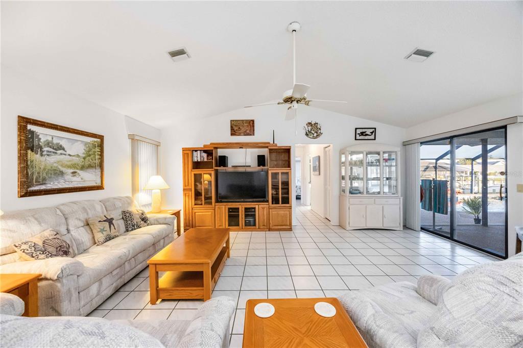 A living room features white tile floors, a vaulted ceiling, and a sliding glass door — 10534 ALPACA CIRCLE, PORT CHARLOTTE, FL