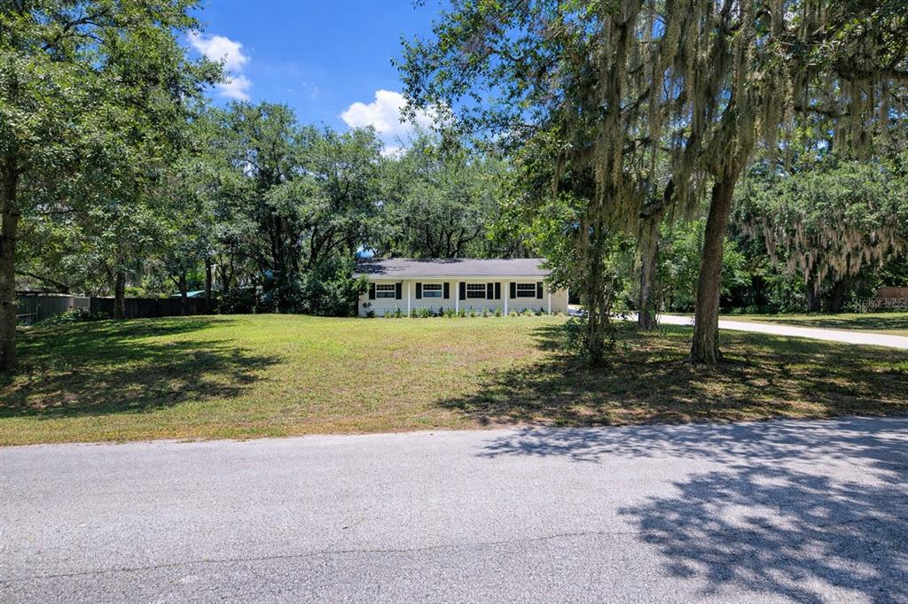 A single-story house with a light-colored exterior sits behind a large, grassy front yard — 3036 LOWERY DRIVE, OVIEDO, FL