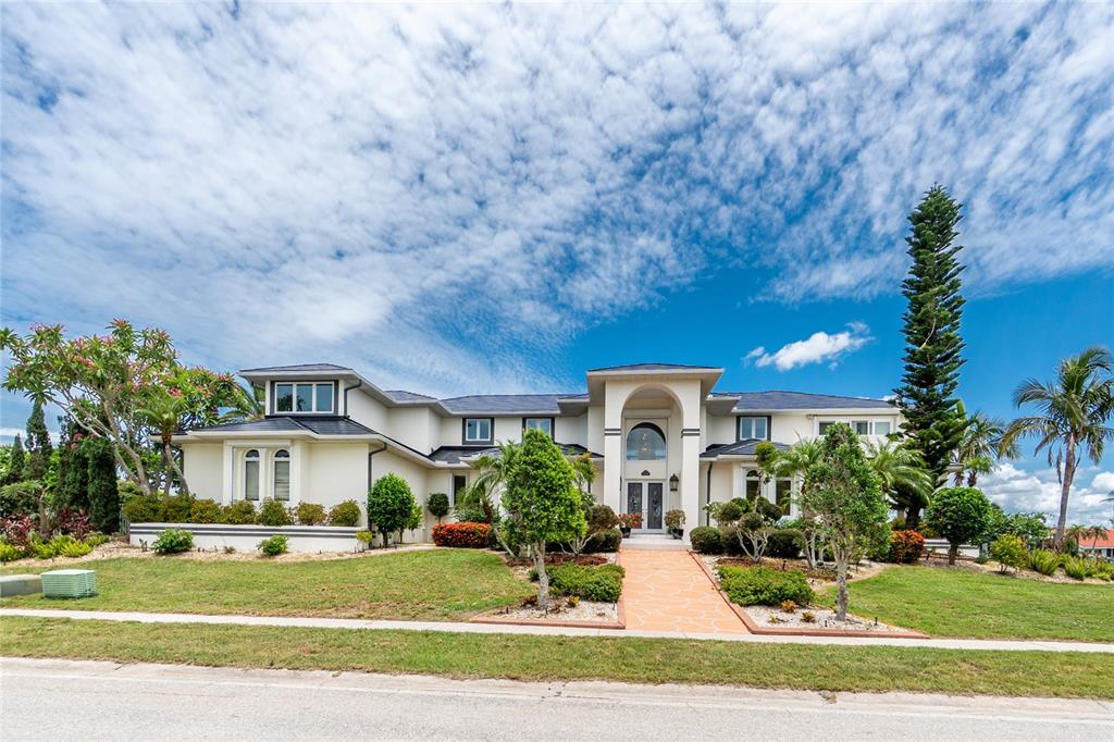 A two-story house with a white stucco facade, arched entryway, and a paved walkway — 202 GEORGE ROAD SE, PORT CHARLOTTE, FL