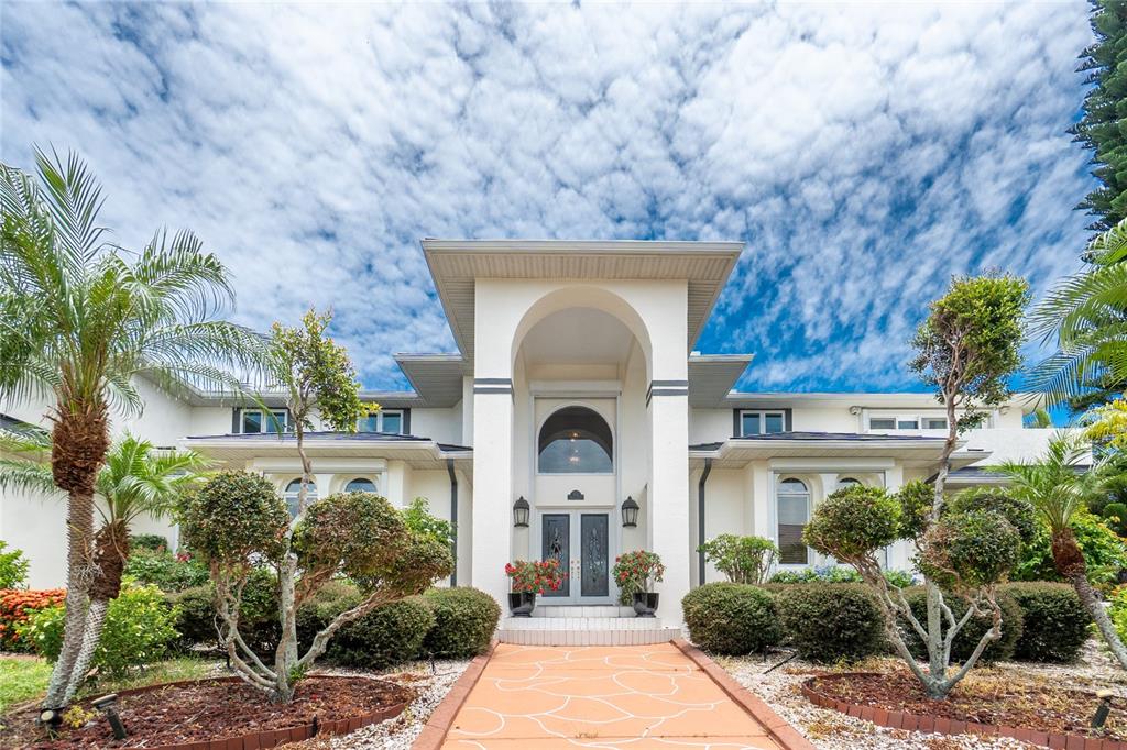 A high-ceilinged living room features a mezzanine balcony, a grand piano, and tile flooring — 202 GEORGE ROAD SE, PORT CHARLOTTE, FL