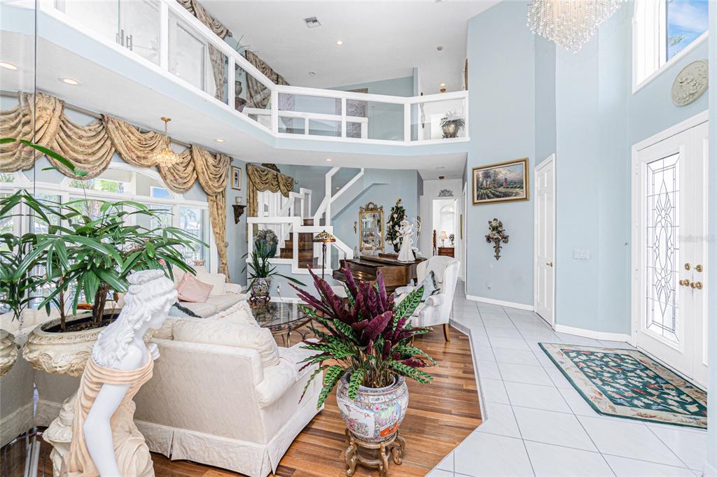 A bright, two-story living room features hardwood floors, a glass coffee table, and large windows — 202 GEORGE ROAD SE, PORT CHARLOTTE, FL