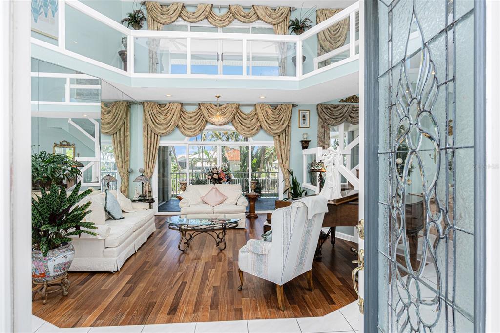A living room features a grand piano, a Christmas tree, and a staircase with railings — 202 GEORGE ROAD SE, PORT CHARLOTTE, FL