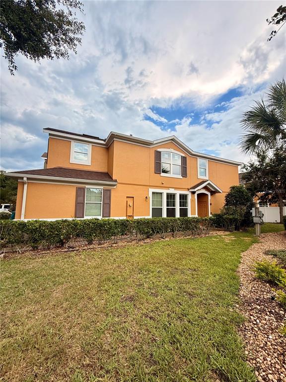 A two-story orange stucco house with a brown roof and a landscaped front yard — 9412 STRONGBARK LANE, ORLANDO, FL