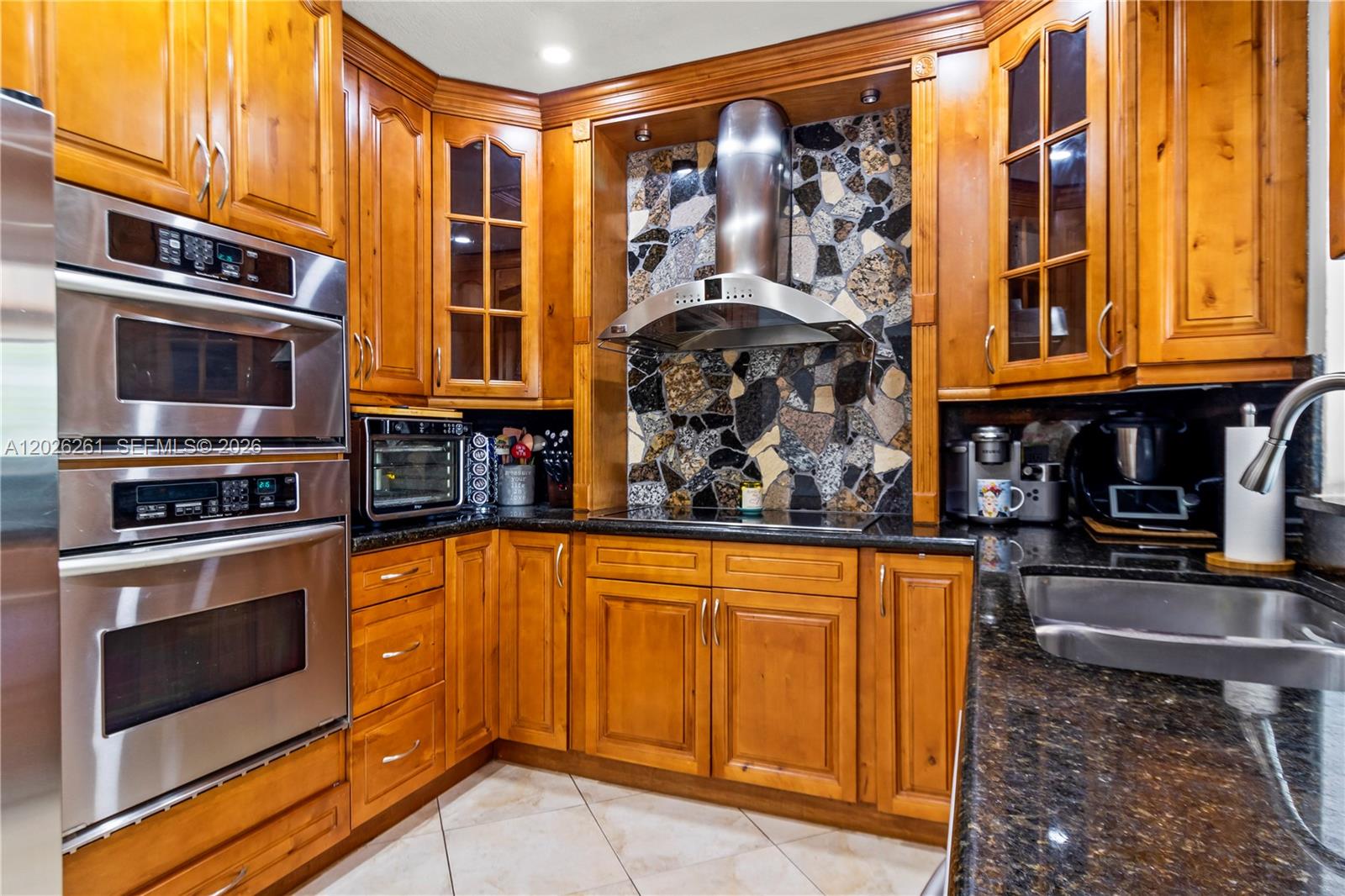 A kitchen features wood cabinets, stainless steel appliances, a stone backsplash, and dark granite countertops — 6250 SW 20 ter, Miami FL 33155, MIAMI, FL