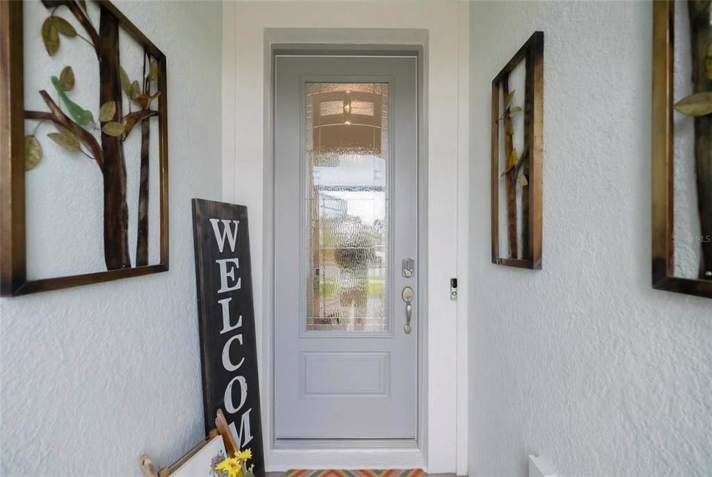 A light gray front door with a glass insert is flanked by decorative wall art — 9426 SW 54TH STREET, OCALA, FL