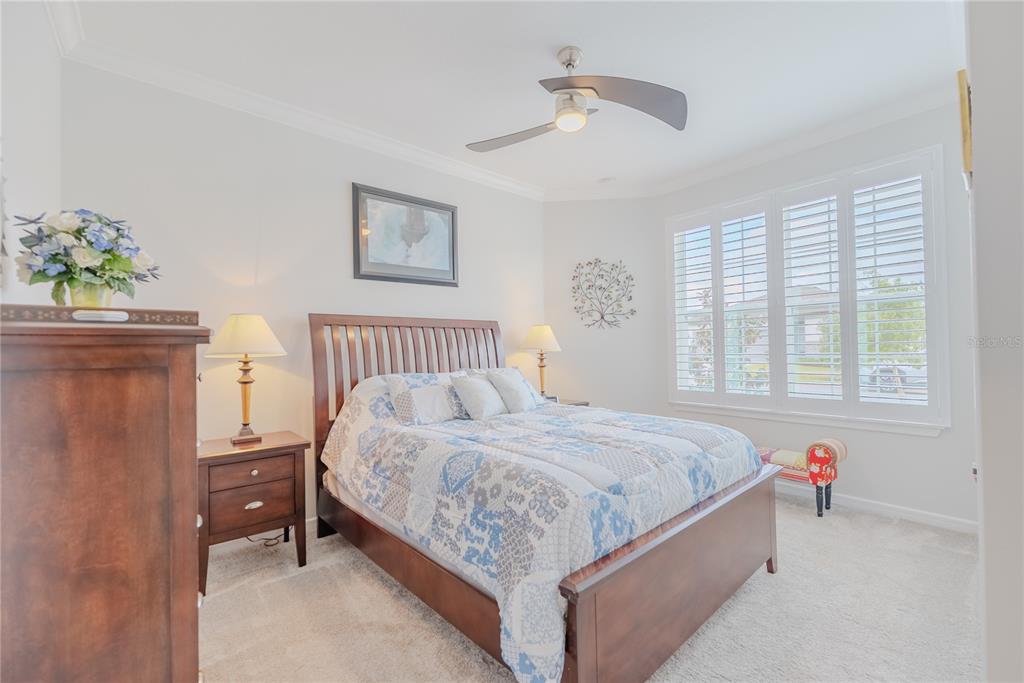 A bedroom features a wooden bed frame, a patterned quilt, and plantation shutters on windows — 9426 SW 54TH STREET, OCALA, FL