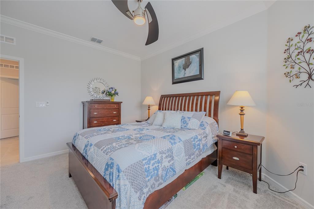 A bedroom features a wooden bed frame, a patterned quilt, and two matching nightstands — 9426 SW 54TH STREET, OCALA, FL