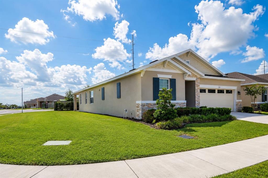 A tan single-story house with stone accents, dark shutters, and a two-car garage — 708 GRIFFON AVENUE, LAKE ALFRED, FL