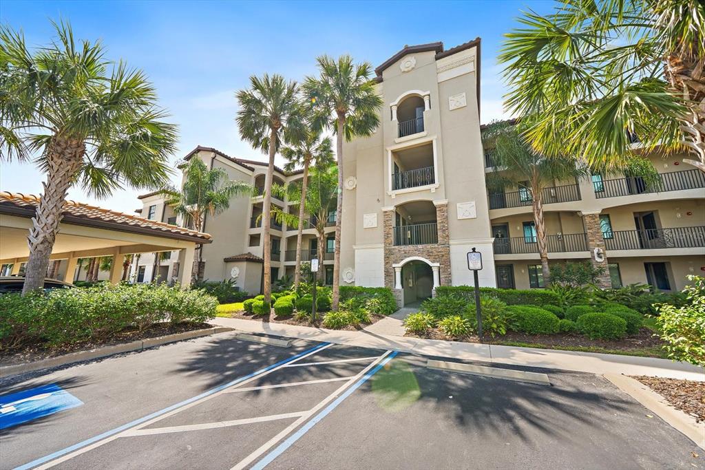 A multi-story apartment building with a covered parking area and palm trees in front — 17006 VARDON TERRACE UNIT 401, BRADENTON, FL