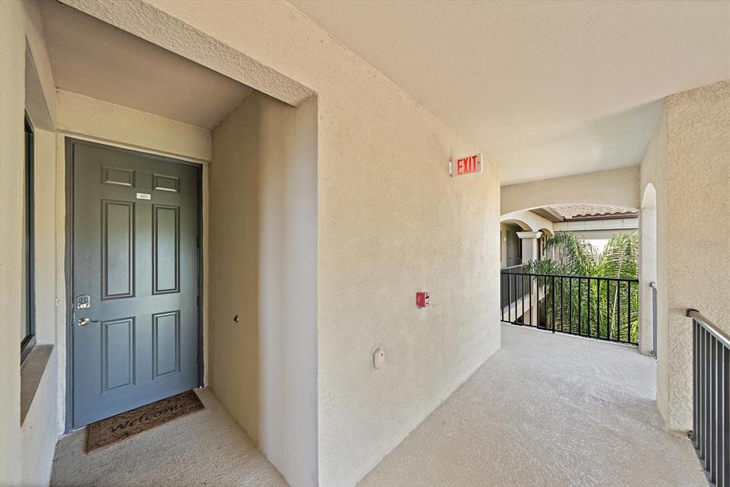 An exterior view of an apartment entrance with a gray door and a balcony railing — 17006 VARDON TERRACE UNIT 401, BRADENTON, FL
