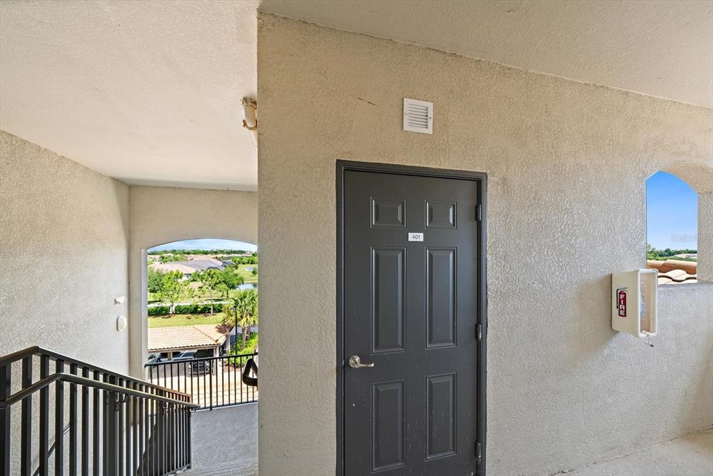 A dark gray apartment door labeled 401 is situated in an outdoor stairwell hallway — 17006 VARDON TERRACE UNIT 401, BRADENTON, FL