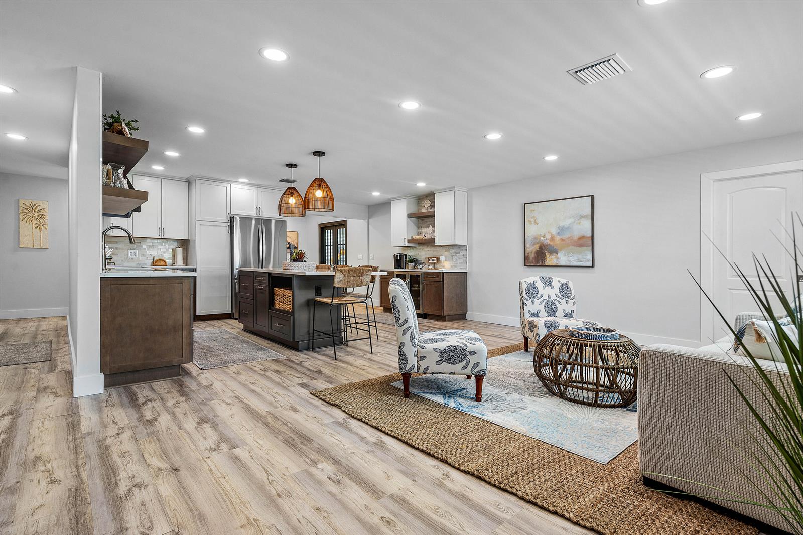 An open-concept kitchen and living area features wood-look flooring, a central island, and coastal decor — 2015 SW 18th Drive, Boynton Beach FL 33426, BOYNTON BEACH, FL