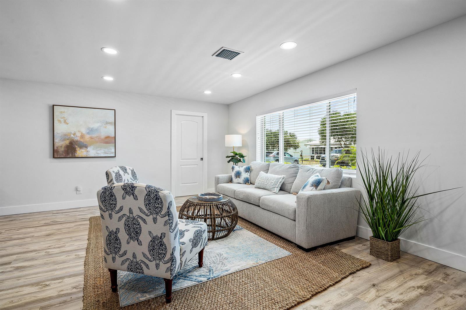 A living room features a grey sofa, patterned armchairs, a round coffee table, and wood flooring — 2015 SW 18th Drive, Boynton Beach FL 33426, BOYNTON BEACH, FL
