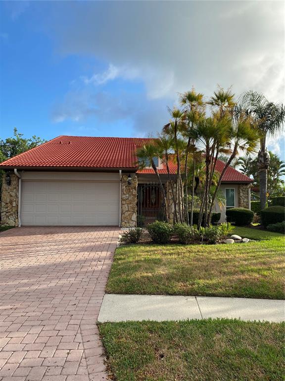 An aerial view shows a suburban neighborhood with houses, a canal, and a tennis court — 7011 PELICAN ISLAND DRIVE, TAMPA, FL