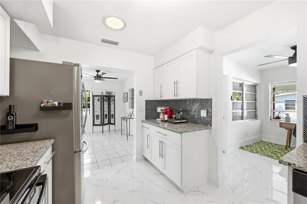 A kitchen with white cabinets, granite countertops, and a dark herringbone tile backsplash — 1147 SHADY REST LANE, NAPLES, FL