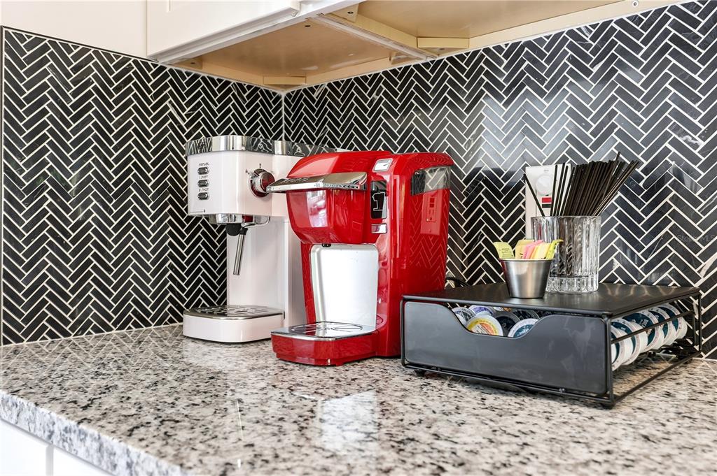 A kitchen counter features two coffee makers and a pod storage rack against a herringbone backsplash — 1147 SHADY REST LANE, NAPLES, FL