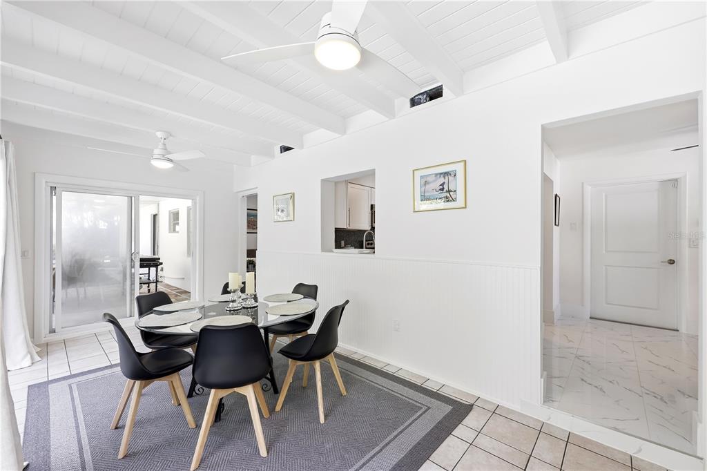 A dining area with a glass table, black chairs, and white beadboard wall paneling — 1147 SHADY REST LANE, NAPLES, FL