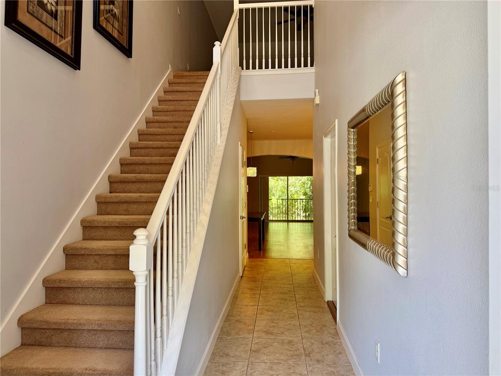 A carpeted staircase with a white railing leads to an upper landing in a foyer — 683 EVENING SKY DRIVE, OVIEDO, FL