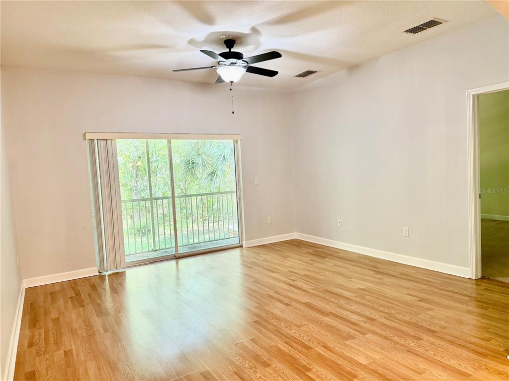 A bedroom with hardwood floors, a ceiling fan, and sliding glass doors leading to a balcony — 683 EVENING SKY DRIVE, OVIEDO, FL