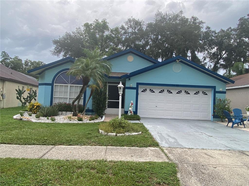 A light blue single-story house with a white garage door and a front palm tree — 1420 WINDJAMMER PLACE, VALRICO, FL