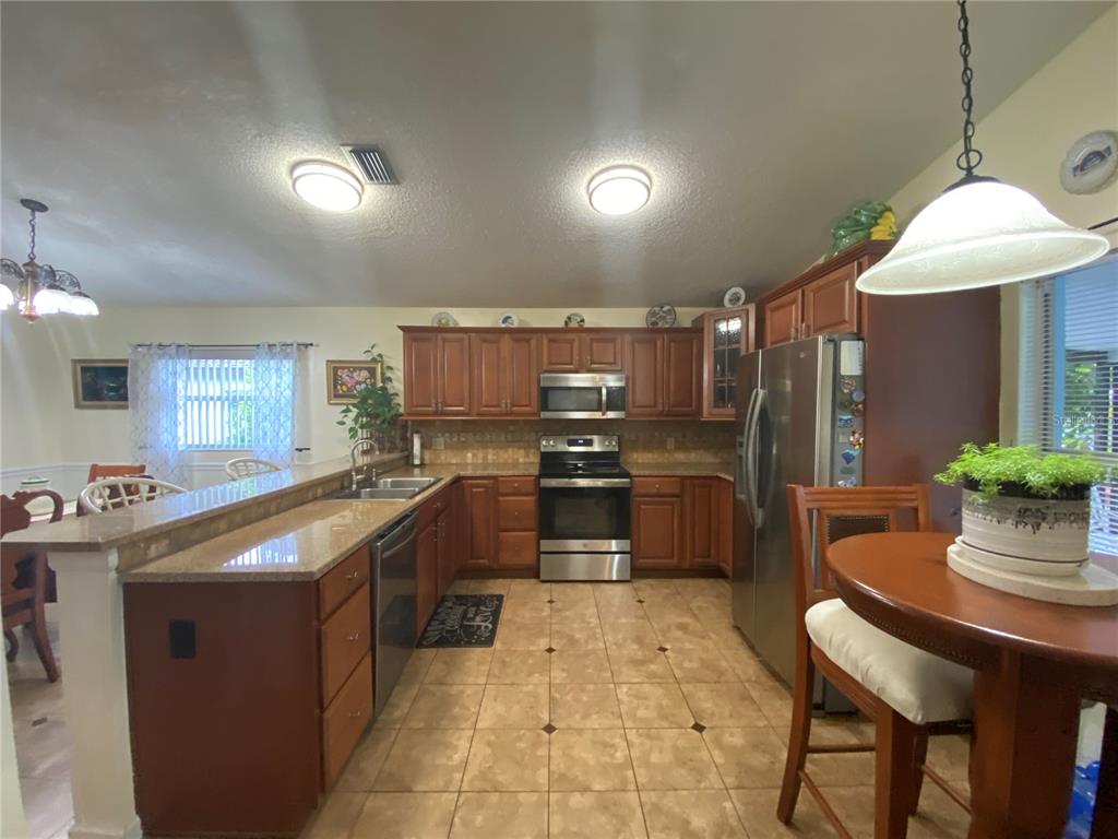 A kitchen with wood cabinets, stainless steel appliances, and a breakfast nook with a table — 1420 WINDJAMMER PLACE, VALRICO, FL