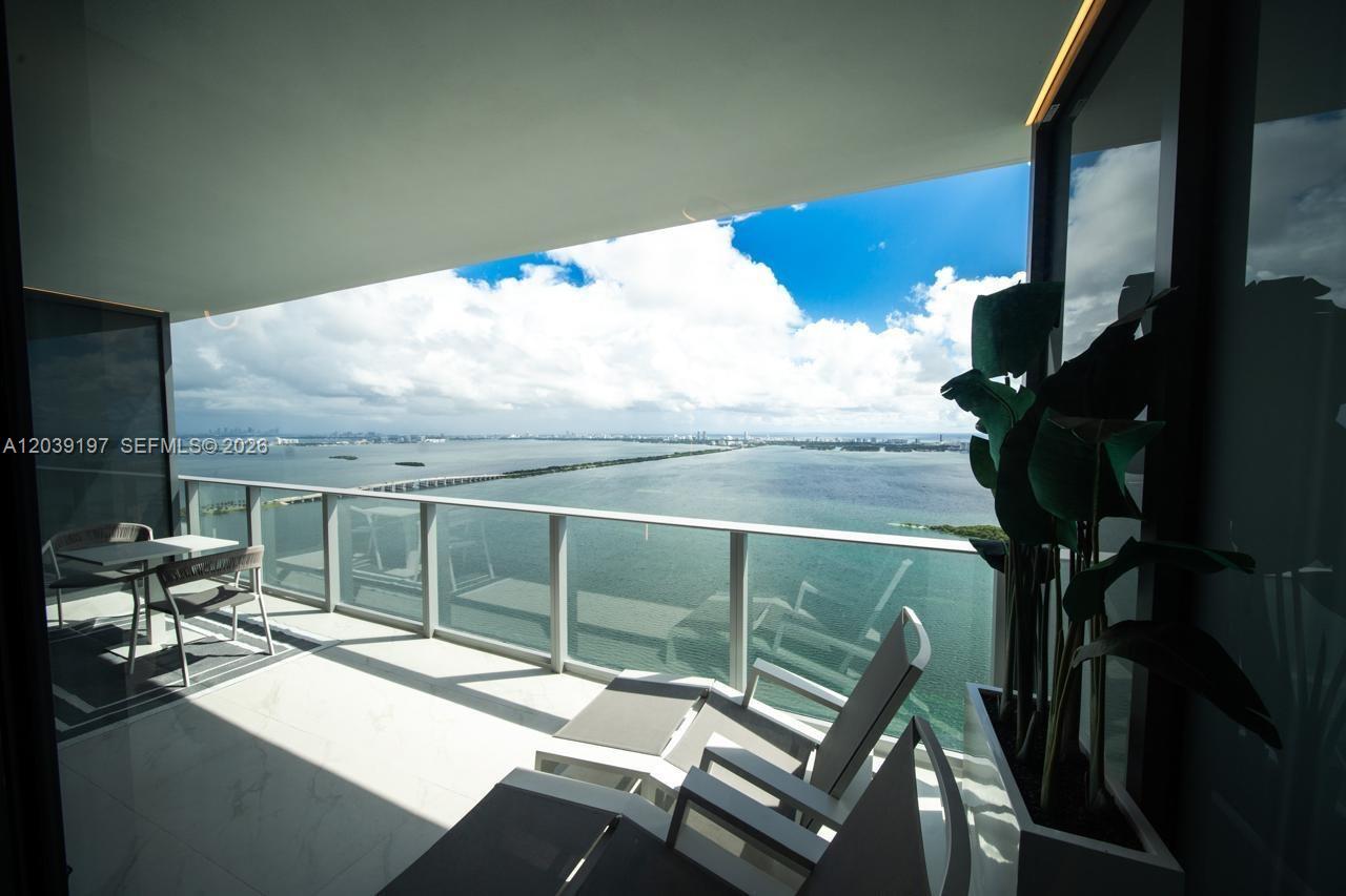 A balcony with white tile flooring overlooks a large body of water and a bridge — 711 NE 23rd Ter # 5304B, Miami FL 33137, MIAMI, FL