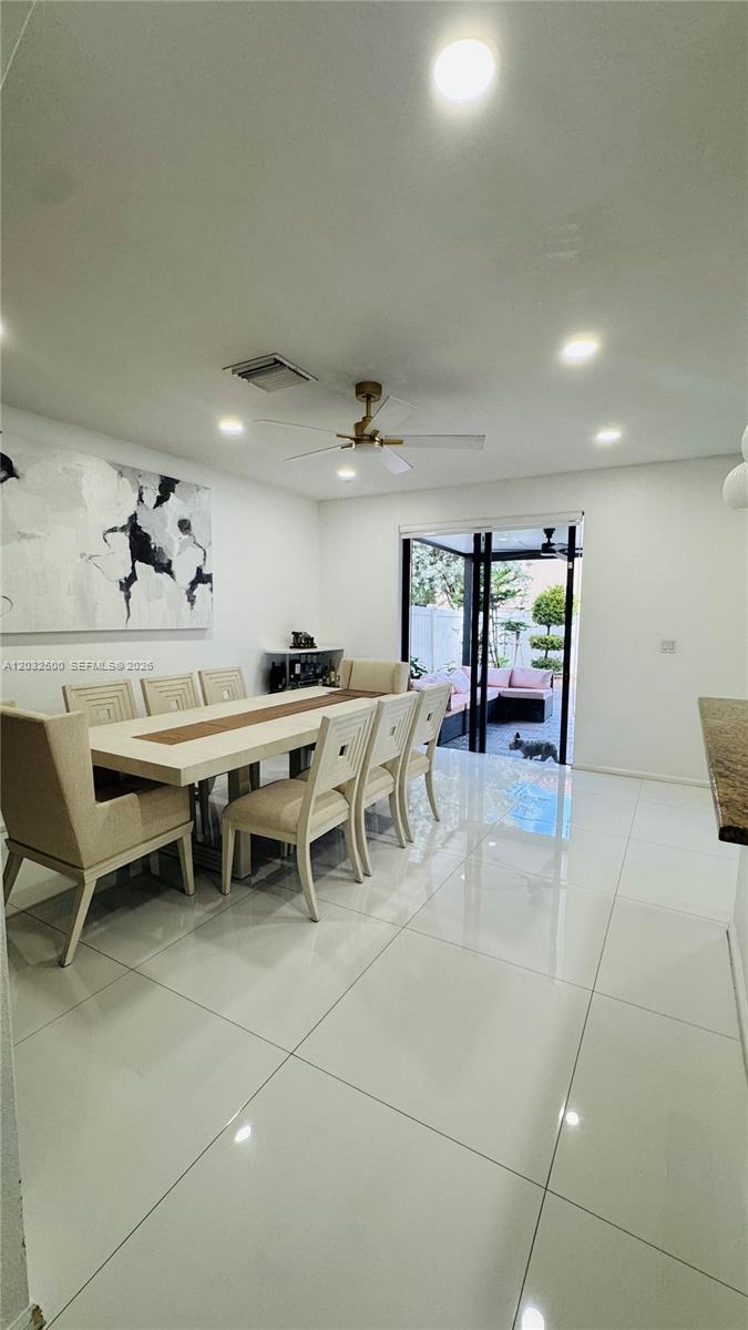 A dining room features a long table, upholstered chairs, white tile floors, and a patio view — 3355 W 90th Ter, Hialeah FL 33018, HIALEAH, FL