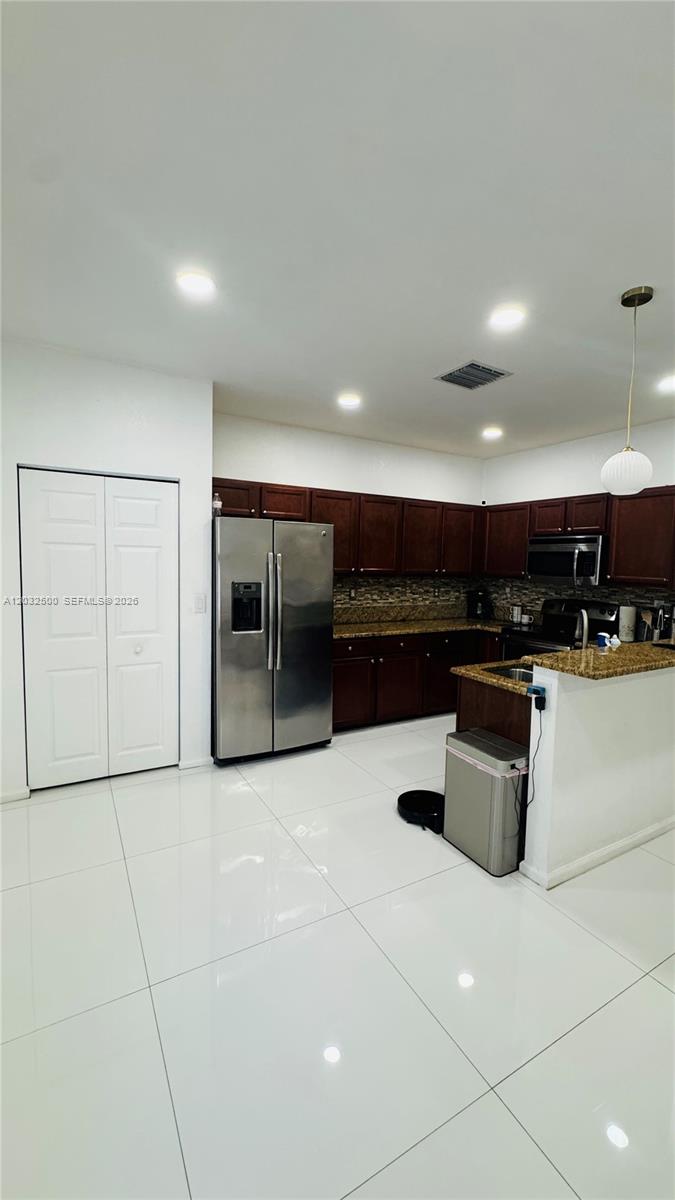 A kitchen features dark wood cabinets, granite countertops, stainless steel appliances, and white tile flooring — 3355 W 90th Ter, Hialeah FL 33018, HIALEAH, FL