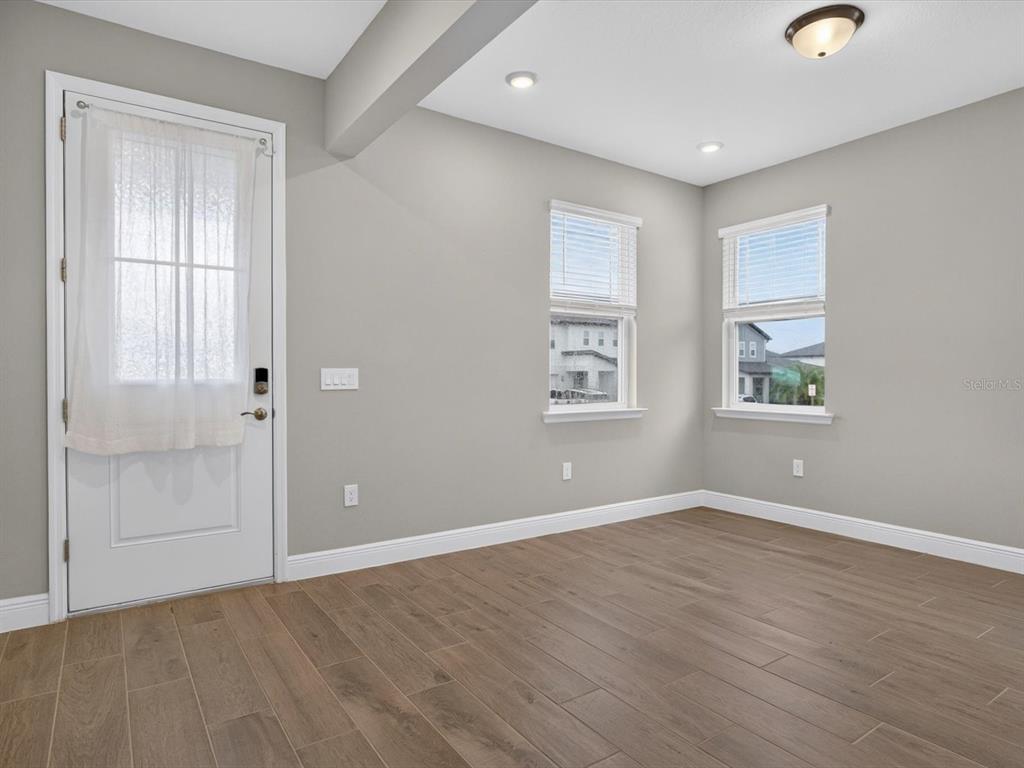 An empty room with gray walls, wood-look tile flooring, two windows, and a white door — 2292 BEAR PEAK RD. ROAD, MINNEOLA, FL