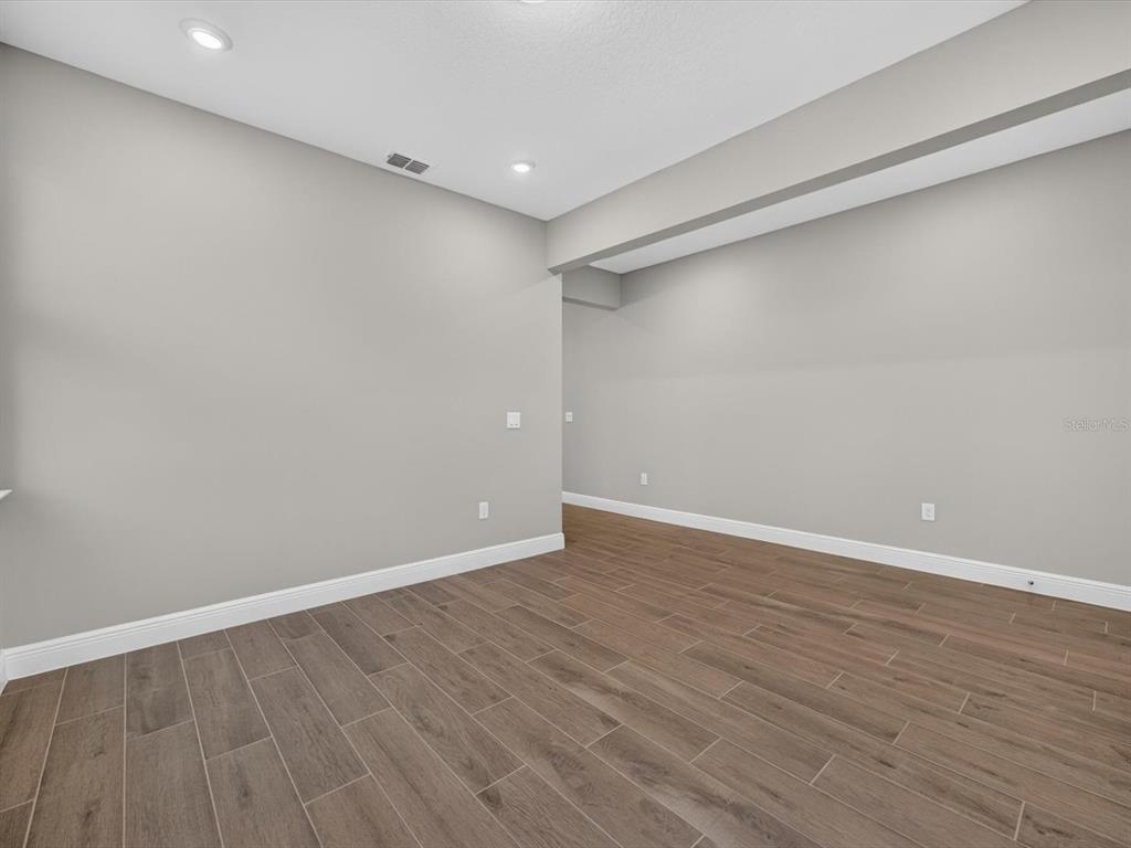 An empty room features light gray walls, recessed lighting, and wood-look tile flooring — 2292 BEAR PEAK RD. ROAD, MINNEOLA, FL