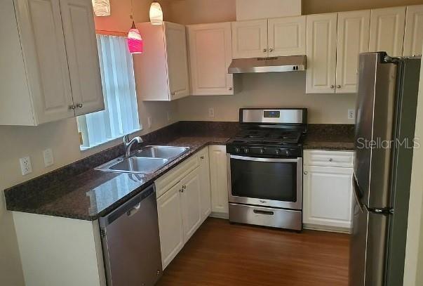 A kitchen features white cabinets, dark countertops, stainless steel appliances, and wood-look flooring — 815 W REMBRANDT WAY UNIT 424, INVERNESS, FL