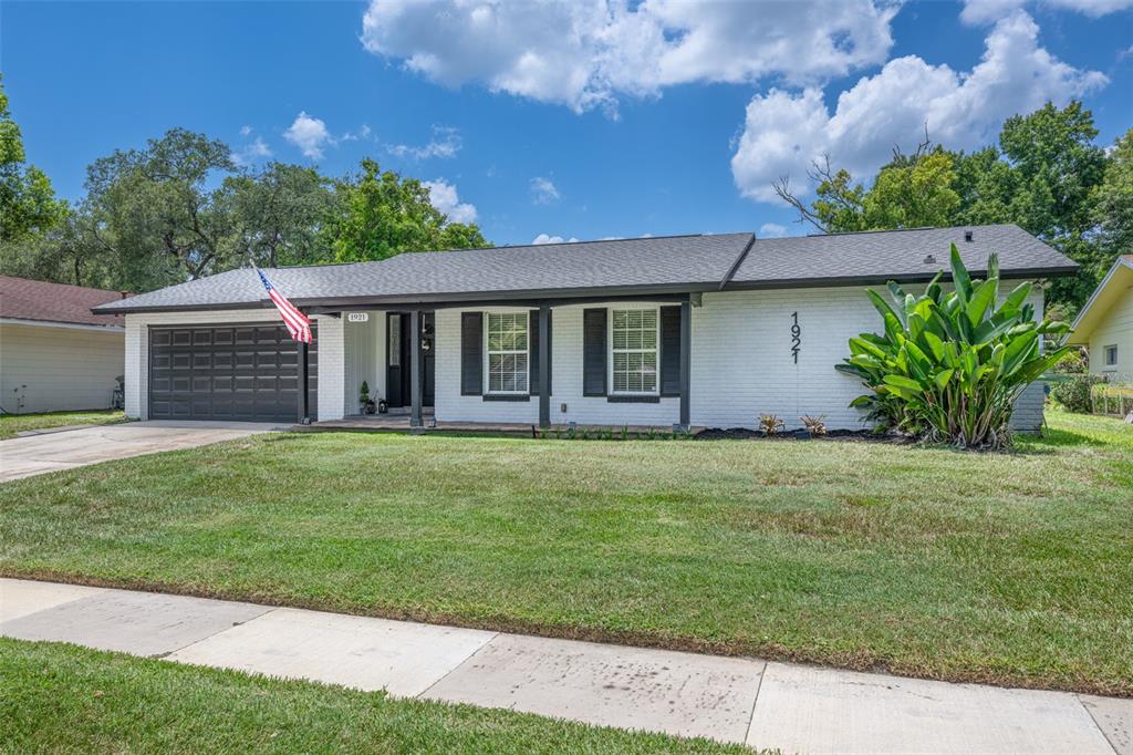 A single-story white brick house with a dark roof, garage, and shutters — 1921 WINNEBAGO TRAIL, FERN PARK, FL