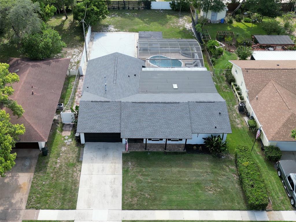 An aerial view shows a single-story house with a grey roof, pool enclosure, and driveway — 1921 WINNEBAGO TRAIL, FERN PARK, FL