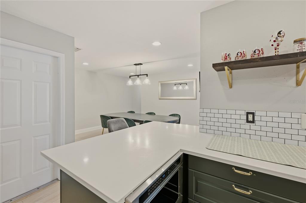A kitchen island with a white countertop overlooks a dining area with a modern chandelier — 1921 WINNEBAGO TRAIL, FERN PARK, FL