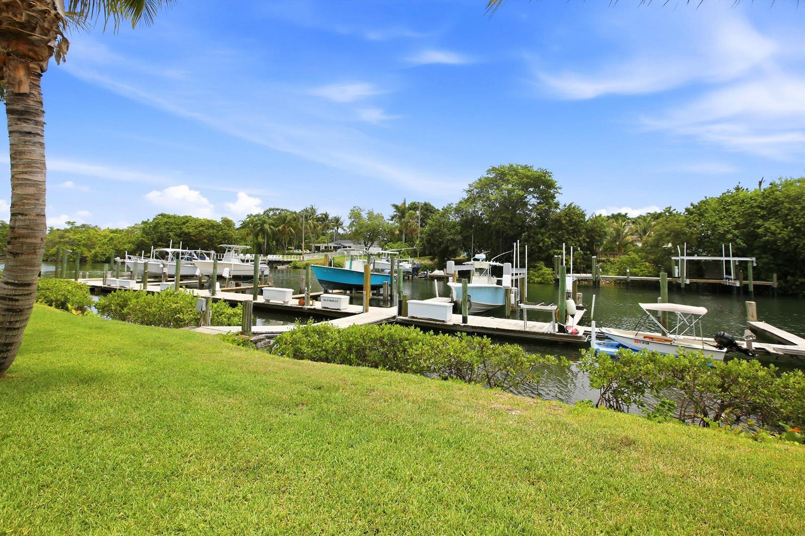 A grassy lawn overlooks a canal with several docked boats and wooden piers — 412 Southwind Drive # E2, North Palm Beach FL 33408, NORTH PALM BEACH, FL