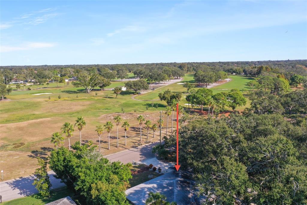 An aerial view shows a house roof with a red arrow pointing toward the golf course — 951 GREENWAY AVENUE, DUNEDIN, FL