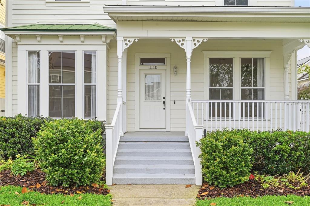A white house exterior features a front porch with steps, a bay window, and landscaping — 1110 RUSH COURT, CELEBRATION, FL