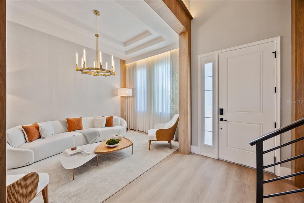 A bright living room features a curved white sofa, a tiered coffee table, and wood accents — 16077 BARKLY RIDGE COURT, WINTER GARDEN, FL