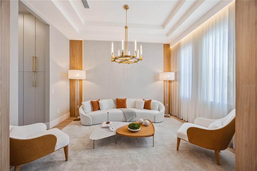 A modern living room features a curved white sofa, two armchairs, and a gold chandelier — 16077 BARKLY RIDGE COURT, WINTER GARDEN, FL