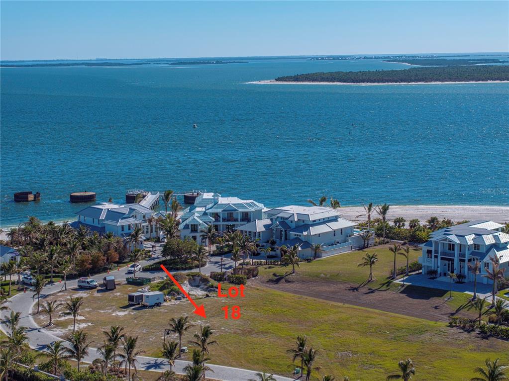 An aerial view shows a vacant waterfront lot marked 18 near several large coastal homes — 869 HILL TIDE LANE, BOCA GRANDE, FL