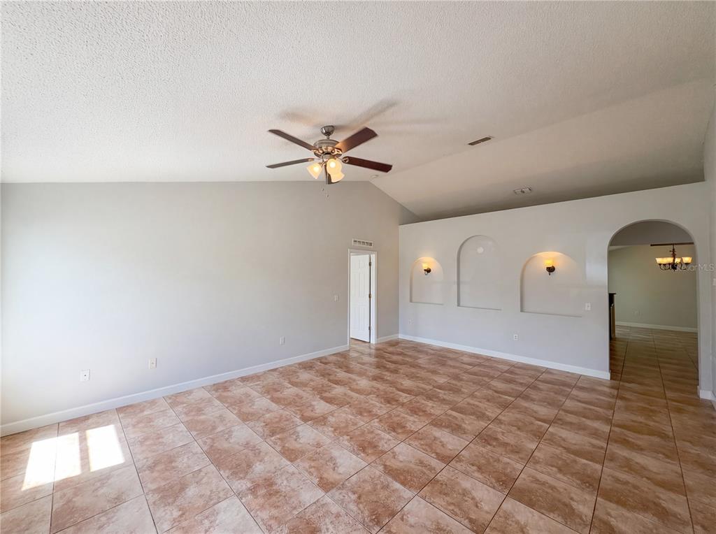A spacious living room features vaulted ceilings, tile flooring, and three arched wall niches — 107 HERRING WAY, KISSIMMEE, FL