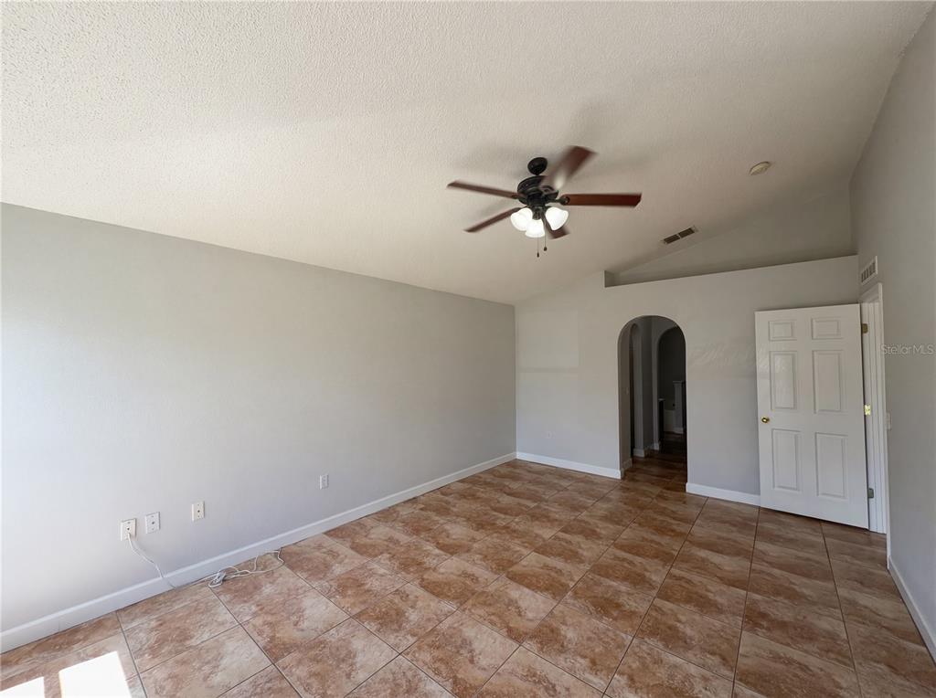 An empty room with light gray walls, brown tile flooring, and a ceiling fan — 107 HERRING WAY, KISSIMMEE, FL